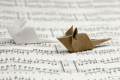 two origami birds sitting on top of sheet music