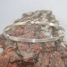 A simple design--four plain square sterling silver wires for a bangle-style look. Pure, uncluttered lines, and stackable with most of my other wirewrapped bracelets! An excellent choice for a graduation, birthday, or holiday gift for that favorite lady in your life. The built-in hook and eye-type clasp is easy to get on and off. Choose the size you want from the variations listed, and get a perfect, comfortable fit. Classic Band Bracelets As A Gift, Classic Band Bracelets As Gifts, Classic Band Bracelets For Gifts, Classic Band Bracelets Perfect As Gifts, Classic Band Bracelets Perfect For Gifts, Handmade Adjustable Minimalist Bangle, Minimalist Hand Wrapped Bangle Bracelet, Modern Band Bracelet As Gift, Adjustable Bangle Bracelet With Simple Design