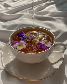 a cup filled with water and flowers on top of a saucer