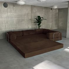 a large brown couch sitting on top of a white floor next to a potted plant