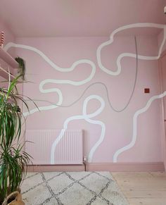 a pink room with white lines painted on the wall and a plant next to it