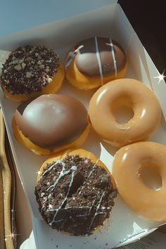 a box filled with lots of different flavored donuts on top of a table