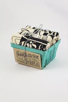 several pieces of fabric wrapped in twine and tied together, sitting in a teal box