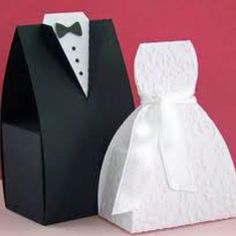 two black and white paper boxes with bow ties on them, one has a tuxedo in it