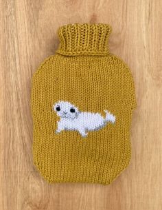 a yellow knitted hot water bottle with a white dog on it's side