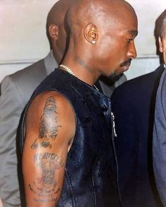 a bald man wearing a leather vest and tattoos