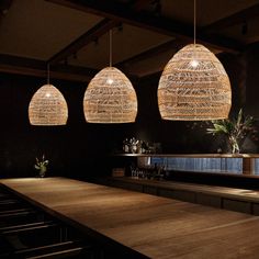 three lights hanging from the ceiling above a wooden bar with stools in front of it