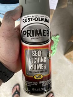 a person holding a can of primer spray in their left hand with the other hand