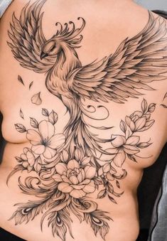 a woman's back with tattoos on her stomach and flowers in the lower part