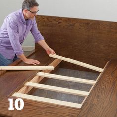 a man is working on the bottom part of a bed frame with no mattresses