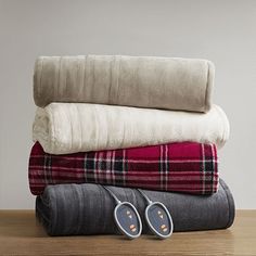 three blankets stacked on top of each other with slippers sitting next to one another