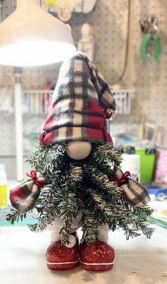 a small christmas tree with red shoes and a plaid hat on it's head