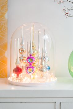 an assortment of colorful glass objects on a white shelf