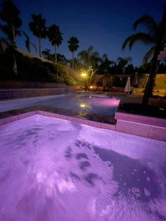 an outdoor swimming pool at night with purple lighting