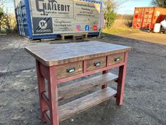 a wooden table sitting on top of a dirt field next to a blue box truck