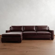 a brown leather couch sitting on top of a wooden floor next to a white wall