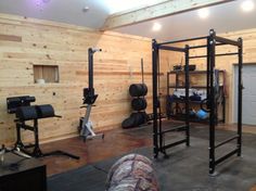 a home gym with wooden walls and black metal equipment on the floor in front of it