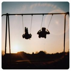 two people on swings in the sky at sunset