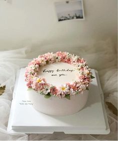 a birthday cake decorated with flowers on top of a white box that says happy birthday to you