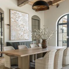 a dining room table and chairs in front of a large painting