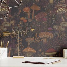 a desk with a notebook, pen and pencils on it in front of a wallpapered background