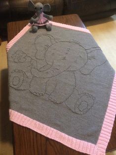 an elephant blanket on top of a coffee table with a stuffed animal sitting on it