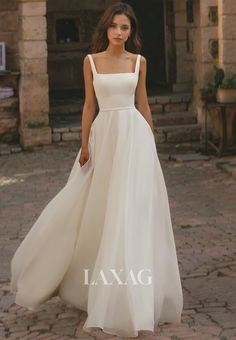 a woman in a white dress is standing on a brick walkway with the words laxag written