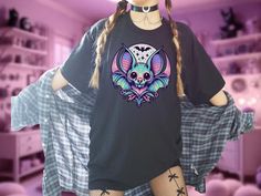 Embrace your dark and whimsical style with this unique Pastel Goth Bat Shirt featuring a striking moon design. Perfect for lovers of Yami Kawaii and Fairy Kei fashion, this Pastel Grunge Shirt will make a statement in any wardrobe. The pink kawaii accents add a touch of sweetness to this Harajuku Kawaii tee, making it the perfect gift for Goths who love to mix edgy and cute styles. Stand out from the crowd with this one-of-a-kind shirt that embodies the essence of pastel goth fashion. To browse Harajuku Style Halloween Short Sleeve Tops, Emo Short Sleeve Tops For Cosplay, Short Sleeve Emo Tops For Cosplay, Harajuku Tops For Halloween, Kawaii Halloween Graphic Print Tops, Emo Cosplay T-shirt With Crew Neck, Harajuku Style Top For Halloween, Pastel Goth Short Sleeve T-shirt For Streetwear, Emo Anime Print Tops For Halloween