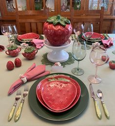 a table set with plates, utensils and strawberries on top of it