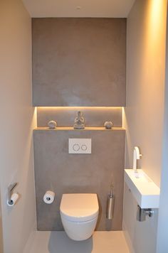 a white toilet sitting inside of a bathroom next to a wall mounted faucet