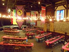 tables and chairs are set up in the middle of a room with banners hanging from the ceiling