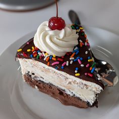 a piece of cake with sprinkles and a cherry on top sits on a plate