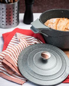 an iron skillet sitting on top of a wooden cutting board next to a red and white towel