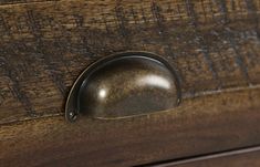 a close up of a drawer with a metal handle on the bottom and wood grained surface