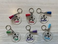 six keychains with musical notes and tassels on them, all in different colors