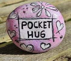 a painted rock sitting on top of a wooden bench with the words pocket hug written on it