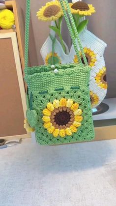 a green crocheted bag with sunflowers in the front and bottom part