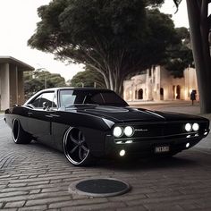 a black muscle car parked in front of a house