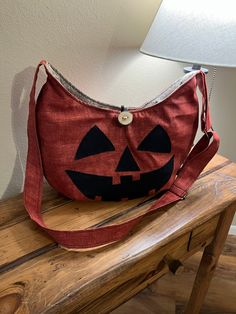 "This pumpkin bag is sure to conjure up the Halloween spirit in every outfit it's added to. Wear it facing out for a jack-o-lantern styled night or facing in for a less Halloween-ish and more fall-ish look! Handmade crossbody bag. Rust orange durable canvas fabric handbag with adjustable strap. Strap measures 24\" to 48\" and can be worn as a crossbody bag or shoulder purse. Beige upholstery fabric interior with 6 inside pockets. Constructed with a deep rust orange canvas outer. Bag measures: 16 Orange Upholstery Fabric, Pumpkin Bag, Fabric Handbags, Duck Cloth, Gift For Sister, Orange Bag, Rust Orange, Dec 30, Halloween Spirit