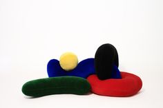 three different colored pillows sitting next to each other on a white surface with a yellow ball in the middle