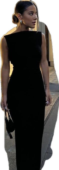 a woman in a black dress is walking down the street with her hand on her hip