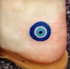 an eyeball tattoo on the foot of a person's foot, with blue ink