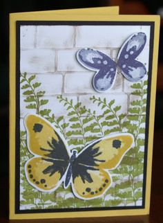 a card with a yellow and blue butterfly on it's side, next to a brick wall