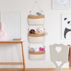 three baskets hanging on the wall with stuffed animals in them and a chair next to it