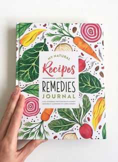 a hand holding up a book that reads my natural recipes and remedies journal