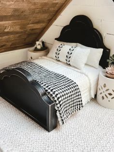 a black and white bed in a bedroom next to a wooden headboard with two planters on it