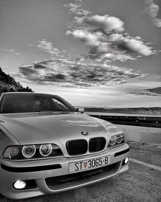 black and white photograph of a bmw car parked on the side of an empty road