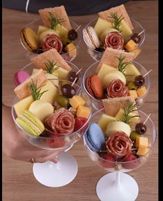 two wine goblets filled with different types of cheeses and crackers on top of each other