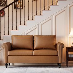 a brown leather couch sitting in front of a stair case