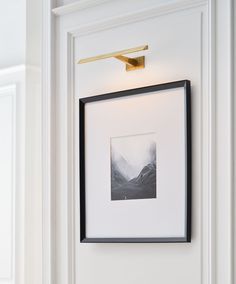 a black and white photo hanging on the wall next to a framed art piece with a light fixture